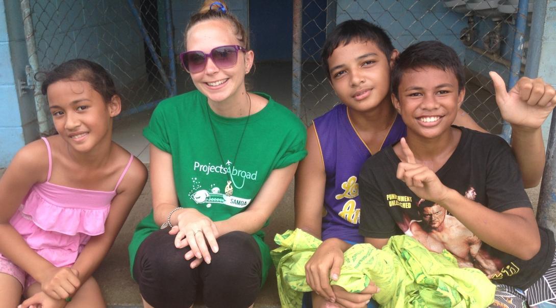 A Projects Abroad volunteer poses with children at a placement in Samoa A volunteer takes a picture with children in Samoa on her trip teenagers